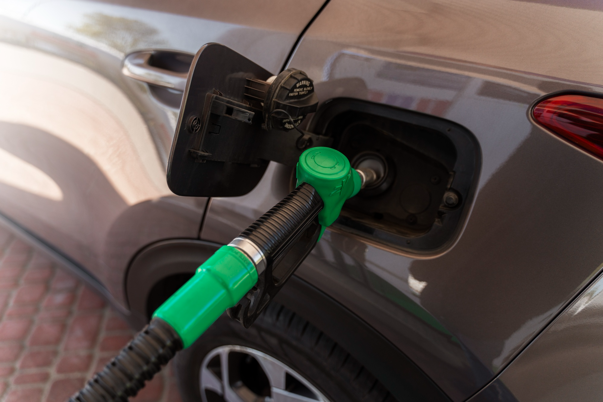 CNG fuel nozzle connected to a car during refuelling at a gas station.