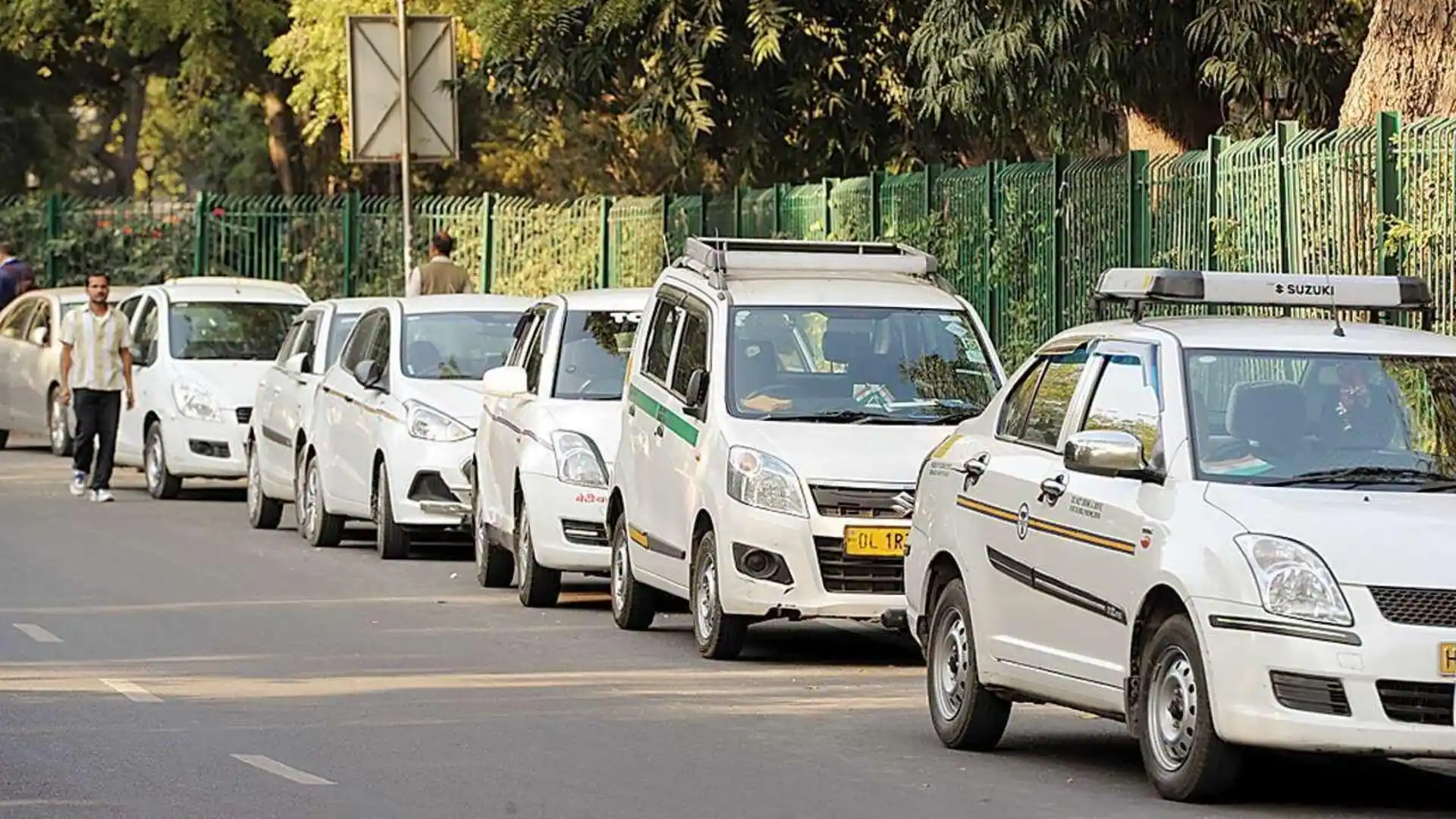 Commercial taxis with yellow number plates parked along a city road
