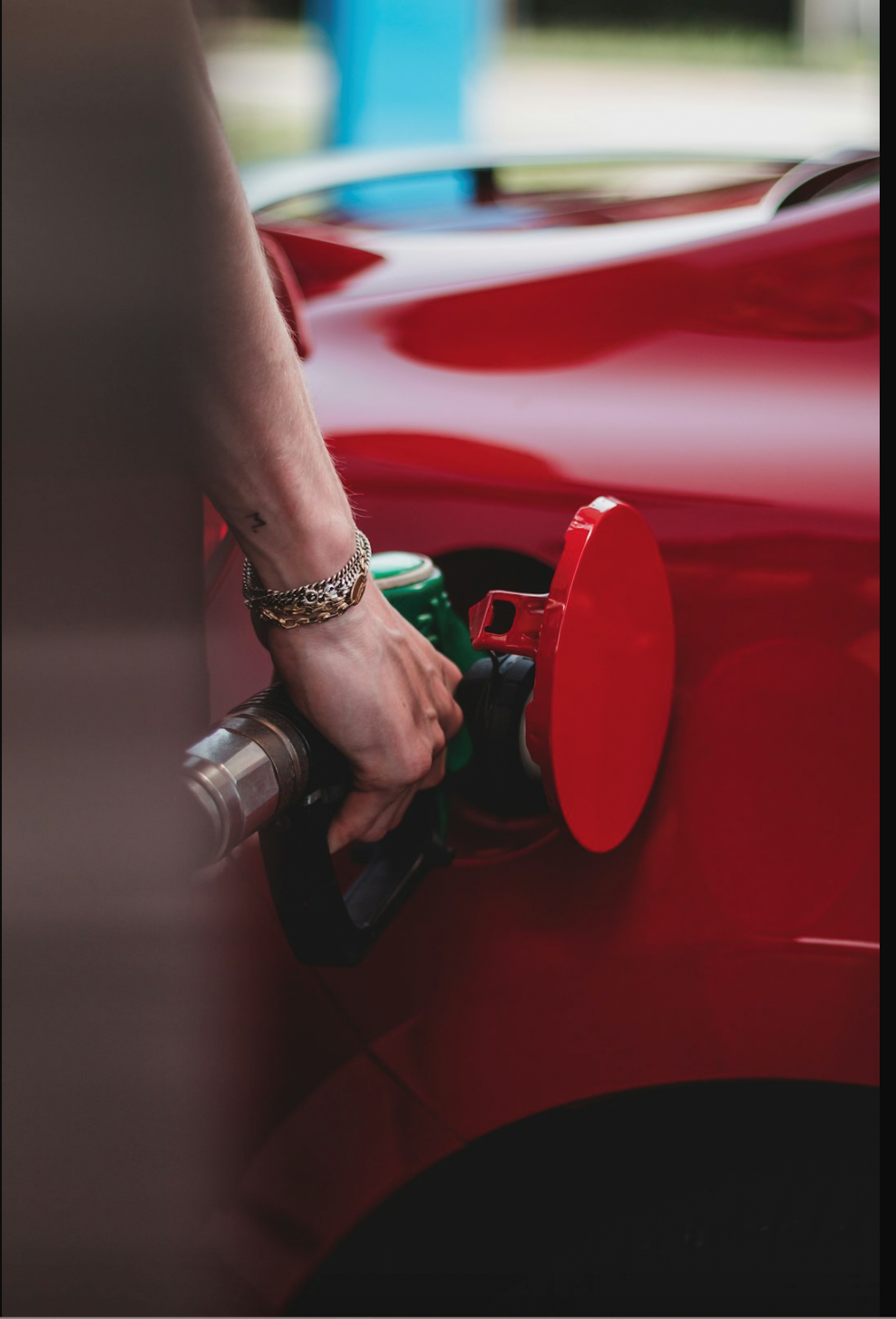 Close-up of a person refueling a car at a petrol station.