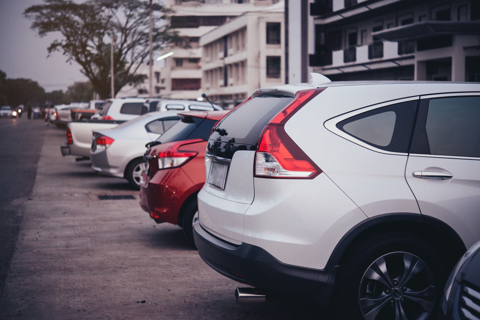 Multiple cars parked beside the road.