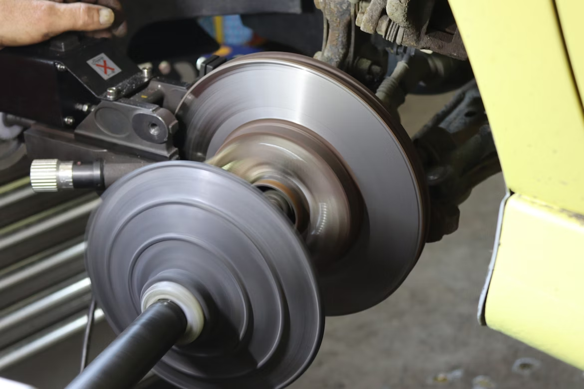 A mechanic working on a car’s disc brake rotor.