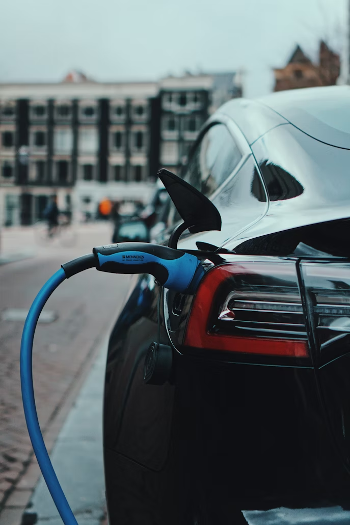 Close-up of an electric car being charged on a city street.