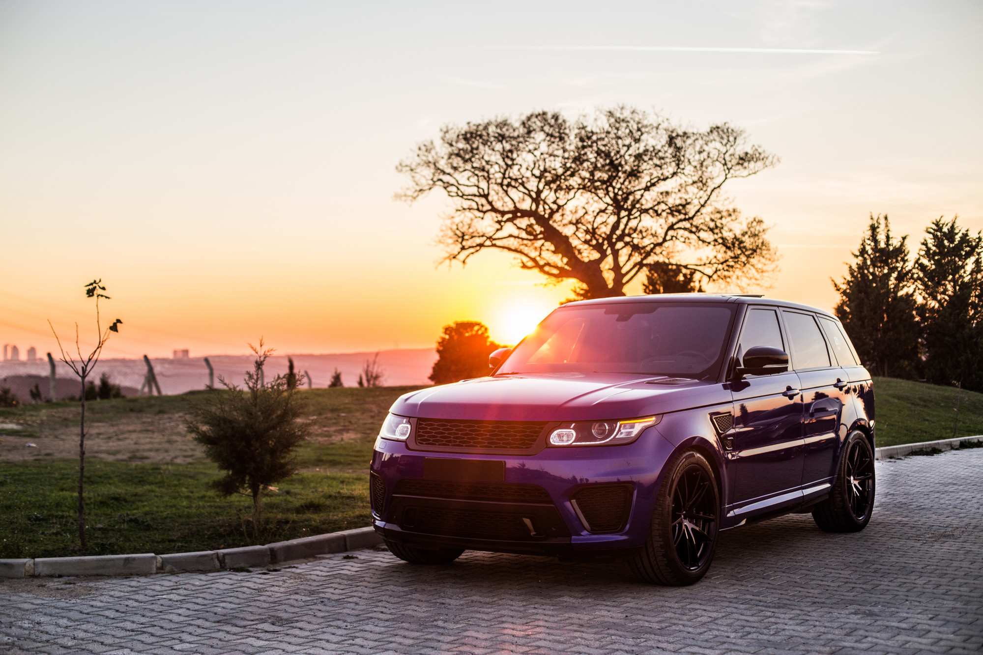 A blue SUV stands against the sunset.