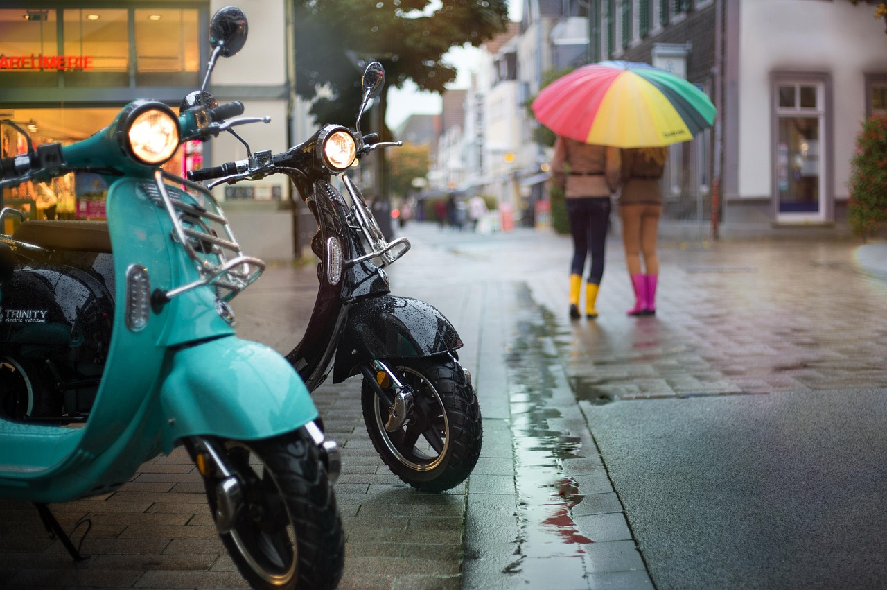 Two lightweight scooters parked on a street.