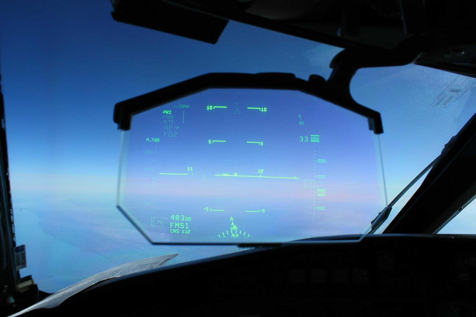 Driver using a touchscreen in a smart car with a Heads Up Display on a mountain road.