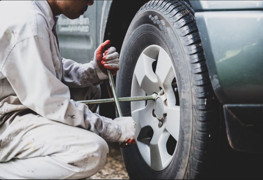 A man fixing a tyre in a vehicle. 