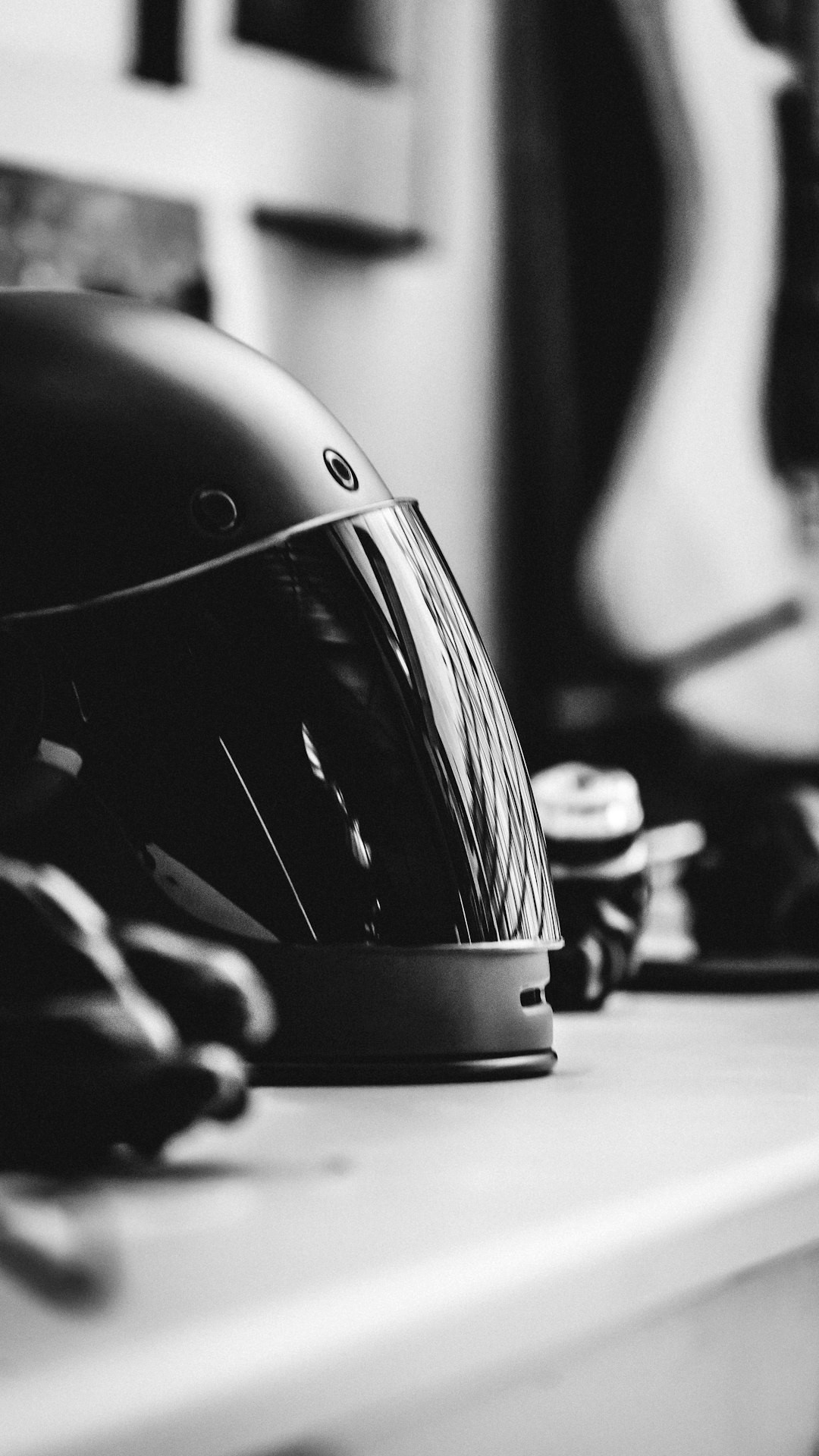 A matte black full-face motorcycle helmet placed on a rustic wooden surface with a blurred outdoor background.