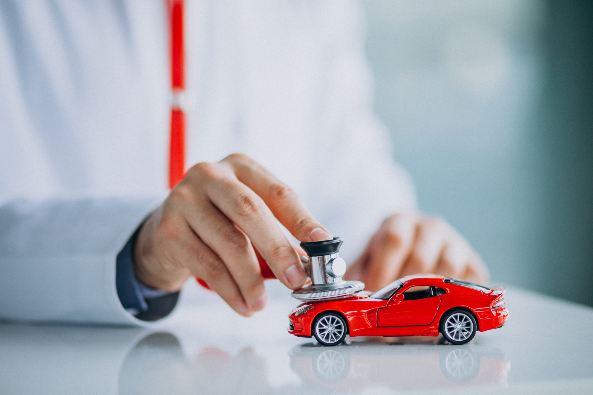 A person examining a model car using a stethoscope.
